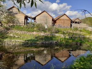 a group of wooden huts next to a body of water at Casa Rustica Fehér Fekete Vendégházak in Sovata