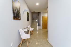 a room with white chairs and a table at PENSIÓN CASA ELENA *** in Arzúa