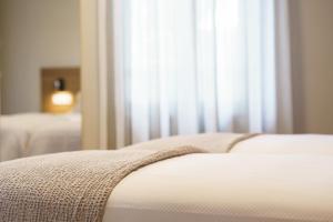 a close up of the edge of a bed with a window at PENSIÓN CASA ELENA *** in Arzúa