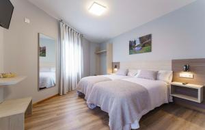 a bedroom with two beds and a mirror at PENSIÓN CASA ELENA *** in Arzúa