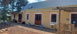 a yellow house with red doors and a fence at Gecko Cottage at Artemis in Franschhoek