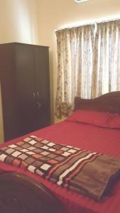 a bedroom with a bed with red sheets and a cabinet at Christa Homestay, AC,near A.J. Hospital, Mangalore in Mangalore