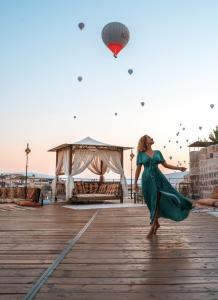 a woman in a green dress flying a kite on a boardwalk at Hera Cave Suites in Göreme