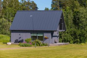 Piesta Kuusikaru riverside cottage in Soomaa region في Kullimaa: منزل رمادي صغير على سقف أسود