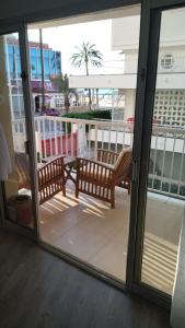 a sliding glass door with two benches on a balcony at Apartamento REX in Benidorm
