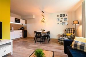 a living room with a table and a kitchen at Róża Sudetów Apartamenty in Duszniki Zdrój