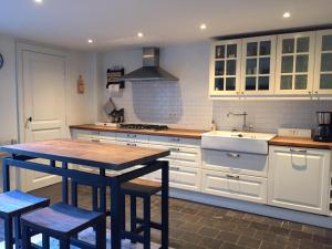 a kitchen with white cabinets and a table with stools at Vakantiehuisje aan de Ijzer in Diksmuide