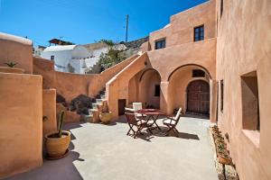 um pátio com cadeiras e uma mesa num edifício em Azalea Houses em Oia