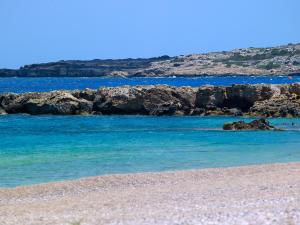 a beach with blue water and rocks in the background at Cavo Marelia in Amoopi