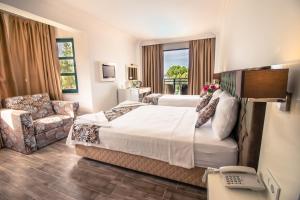 een hotelkamer met een groot bed en een stoel bij Bahar Hotels in Fethiye