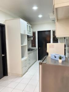 cocina con armarios blancos y encimera en Spanish Villa homestay, en Senawang