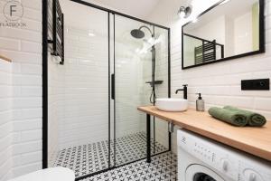 a bathroom with a shower and a washing machine at Flatbook - City Center Apartments Aura 40 in Gdańsk