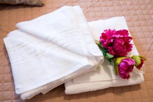 two towels and a bouquet of flowers on a bed at Pura Vida Home in Laganas