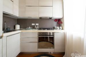 ムラーノにあるDUOMO Murano Apartment with Canal viewの白いキャビネットとオーブン付きのキッチン