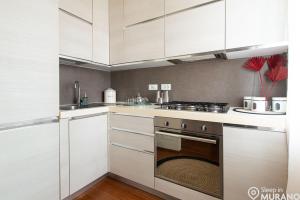 a kitchen with white cabinets and an oven at DUOMO Murano Apartment with Canal view in Murano