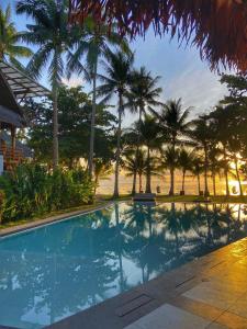 a swimming pool in front of a beach with palm trees at Siargao Island Villas in General Luna