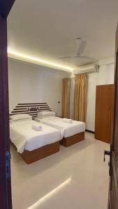 a bedroom with two beds and a ceiling at Beach Walk Villa Maldives in Gulhi