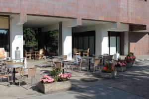 eine Außenterrasse mit Tischen, Stühlen und Blumen in der Unterkunft Hotel Grunewald in Berlin