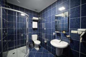 a blue tiled bathroom with a toilet and a sink at Aura Boutique Hotel in Batumi