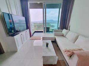a living room with a white couch and a flat screen tv at Delmare Beachfront Bangsaray Premium Condominium in Bang Sare