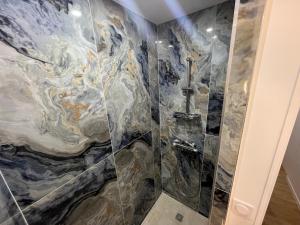 y baño con cabina de ducha de efecto mármol. en Appartement Luxe Jaune en Saint Etienne