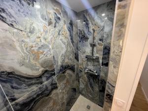 La salle de bains est pourvue d'une cabine de douche à effet marbre. dans l'établissement Appartement Luxe Jaune, à Saint Etienne