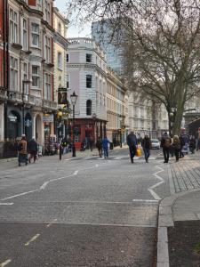 a group of people walking down a city street at 1 Bed Apartment Russell Square in London