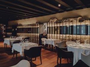 a restaurant with white tables and chairs and windows at Santa María Briones in Briones