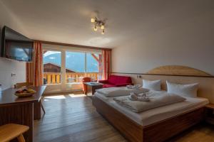 a bedroom with a large bed and a large window at Hotel-Gasthof Andreas in Obertilliach