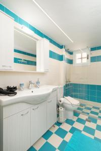 La salle de bains est pourvue d'un lavabo blanc et de toilettes. dans l'établissement Jodi's Pension, à Pitsidia
