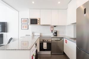 a kitchen with white cabinets and stainless steel appliances at FLH Marquês Charming Flats in Lisbon