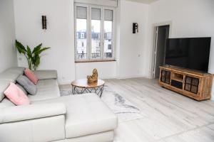 uma sala de estar com um sofá branco e uma televisão de ecrã plano em Le Happy - Épinal centre em Épinal