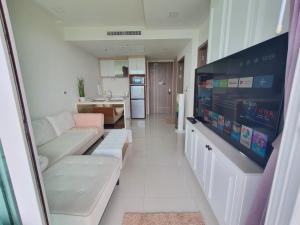 a living room with a couch and a flat screen tv at Delmare Beachfront Bangsaray Premium Condominium in Bang Sare