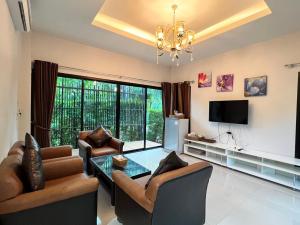sala de estar con mesa, sillas y TV en The Canal Garden Resort, en Ban Huai Sua