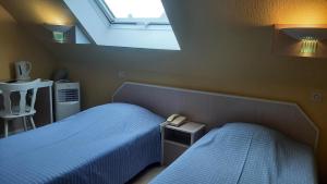 a bedroom with two beds and a skylight at Hôtel Restaurant Aux Deux Roses in Neuf-Brisach