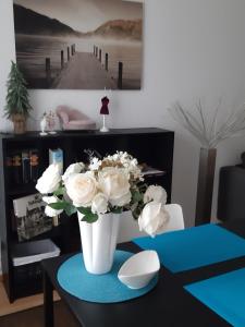 a white vase with white flowers on a table at City Apartment Tübingen-Lustnau in Tübingen +12 photos