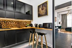 a kitchen with black cabinets and bar stools at Apartament czarny z jacuzzi in Krakow
