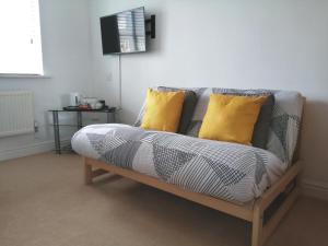 a couch with two yellow pillows in a living room at Lanhydrock View in Bodmin +3 photos