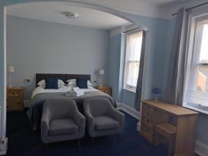 a bedroom with a bed and a chair and windows at The Shirley in Torquay