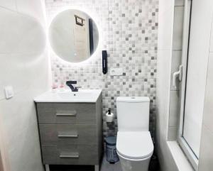 uma casa de banho com um WC, um lavatório e um espelho. em - LUJO - Parking, Maquina Arcade, Wifi y Netflix em Oviedo