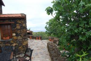 un patio frente a un edificio de piedra con un árbol en Casa Abuela Estebana, en Isora