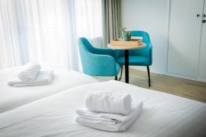 Cette chambre comprend deux lits, une table et une chaise. dans l'établissement Hotel La Source Epen, à Epen