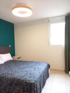 a bedroom with a blue bed and a window at Bel Appartement avec terrasse proche des plages in Saint-Gilles les Bains