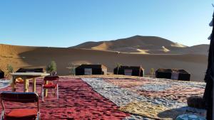 ein Zimmer mit Stühlen und Tischen in der Wüste in der Unterkunft Luxury Camp desert Maroc Tours in M’hamid El Ghizlane