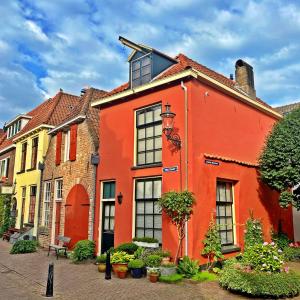 an orange house with windows and plants in a courtyard at Atelier Raamwerk City Apartments Deventer 125m2! in Deventer