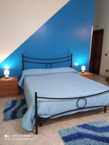 a bedroom with a large bed with a blue wall at Da Rosy in Partinico