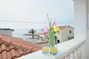 eine Vase mit Blumen und zwei Gläsern auf dem Balkon in der Unterkunft Apartment and rooms SIDRO in Petrcane