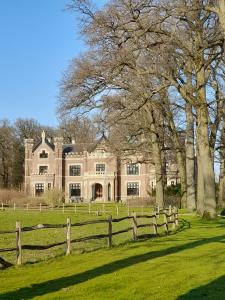 una casa grande con una valla delante en B&B tRust en Barneveld