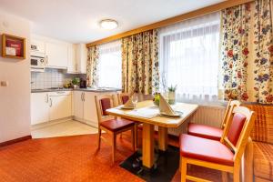 kuchnia z drewnianym stołem i krzesłami oraz kuchnia z kuchnią w obiekcie Hotel Garni Tyola w mieście Ischgl