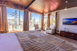 a bedroom with a large bed and large windows at Seclude Shimla, Taraview in Shimla